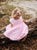 Girl wearing pink hand-smocked dress with white eyelet lace sleeves