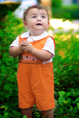 Boy wearing orange hand-smocked spider web Halloween shortall